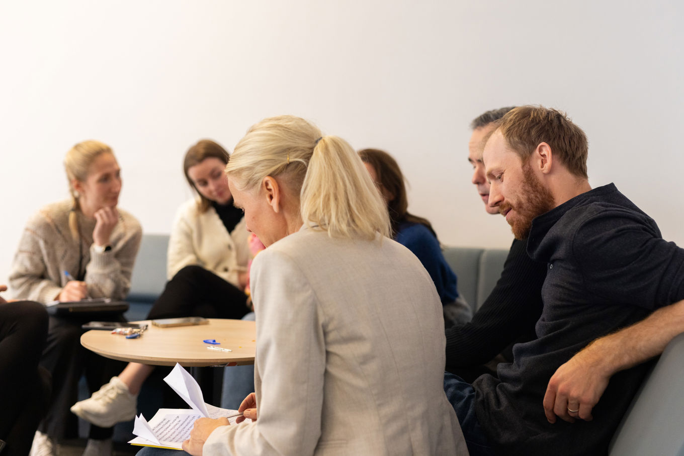 en person og en person som sitter i et rom med andre mennesker