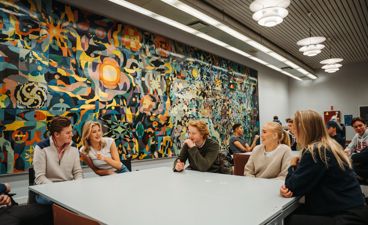 En gruppe mennesker som sitter ved et bord foran et stort kart