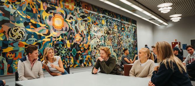 En gruppe mennesker som sitter ved et bord foran et stort kart En gruppe mennesker som sitter ved et bord foran et stort kart