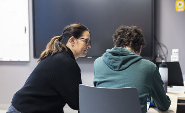 en person og en person som sitter ved et skrivebord